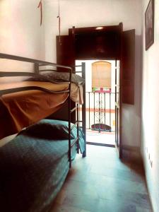 Cette chambre dispose de lits superposés et d'une porte donnant sur un balcon. dans l'établissement One bedroom apartement with city view balcony and wifi at Sevilla, à Séville