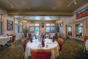 uma sala de jantar com mesas, cadeiras e janelas em Flying Saddle Resort and Steak House em Alpine