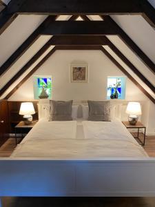 1 dormitorio con 1 cama blanca grande y 2 lámparas en Das Atelier, en Krummhörn