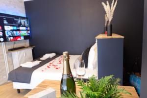 a bottle of champagne on a table next to a bed at Spa & Love - Balnéo - Queen size - Cocooning in Aulnat