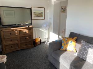 uma sala de estar com uma televisão de ecrã plano e um sofá em High Oak Holiday Cottage em Thirsk
