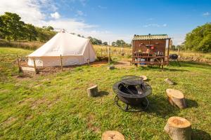 a tent and a grill in a field at Roaches Retreat Eco Glampsite - Hen Cloud View Bell Tent in Upper Hulme