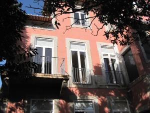 różowy budynek z białymi oknami i balkonem w obiekcie Koolhouse Porto w Porto