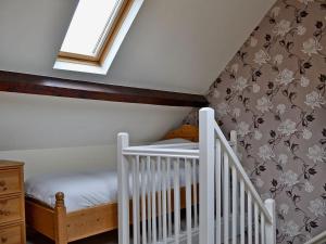 a attic room with a crib and a window at The Carters Cottage in Sedgwick