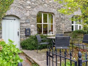 a table and chairs in front of a stone building at The Carters Cottage in Sedgwick