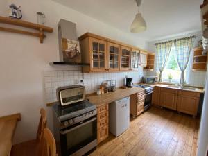 a kitchen with wooden cabinets and a stove top oven at Leonardo Guesthouse in Świeradów-Zdrój +22 photos