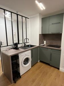 uma cozinha com uma máquina de lavar roupa e um lavatório em Deux pièces cosy à La Croisette em Carrières-sous-Poissy