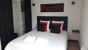 Maison et grande terrasse face mer في سانت ميشيل تشيف تشيف: غرفة نوم بسرير أبيض ومخدات حمراء وسوداء