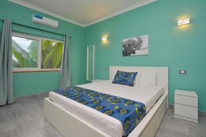 a bedroom with a bed with blue walls and a window at Bless Villa Apartment in Kiwengwa +30 photos