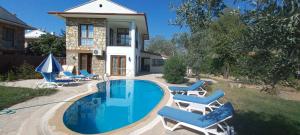 een zwembad met stoelen en een huis bij Ölüdeniz Özel yüzme havuzlu villa 2 in Fethiye