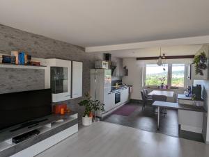 uma cozinha e sala de estar com televisão e mesa em Panoramalounge em Porta Westfalica