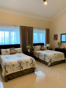 a bedroom with two beds and two windows at Villa Segovia in Cozumel