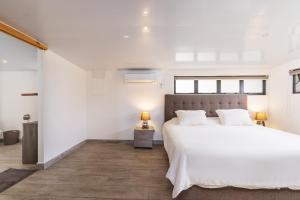 a white bedroom with a large bed and a lamp at Jolie Maison Vue Ocean et Moorea in Punaauia