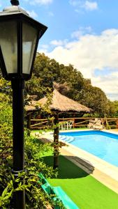 a street light next to a swimming pool with a umbrella at Flor de Lis Casas de Campo in Los Cocos