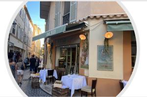 a restaurant with white tables and people walking down a street at Nouveau Loft: vieille-ville, musée Picasso, marché in Antibes