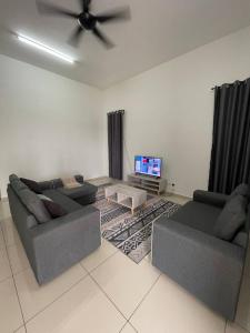 - un salon avec deux canapés et une télévision à écran plat dans l'établissement Bungalow Homestay Jasin, à Malacca