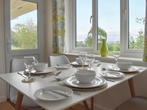 una mesa blanca con platos y vasos. en View Point, en Stokeinteignhead