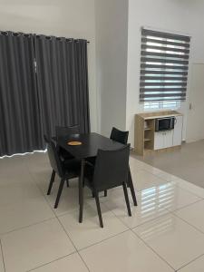 - une table à manger et des chaises noires dans la chambre dans l'établissement Bungalow Homestay Jasin, à Malacca