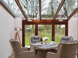 un salón acristalado con mesa, sillas y techo de cristal en Bluebell Cottage - Uk12988, en Monington