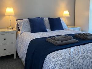 a bed with blue pillows and towels on it at Madryn in Clynnog-fawr