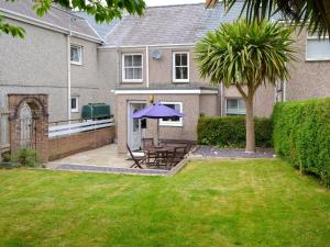 a house with a patio with a table and a blue umbrella at Madryn in Clynnog-fawr