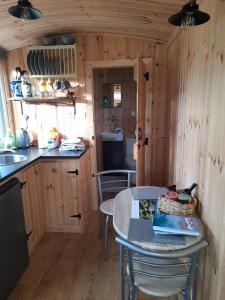 una cocina con mesa y sillas en una cabaña en Sunset View Shepherds Hut en Dalmally