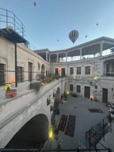 a bridge over a courtyard with a building and a hot air balloon at Salkım Cave House in Göreme