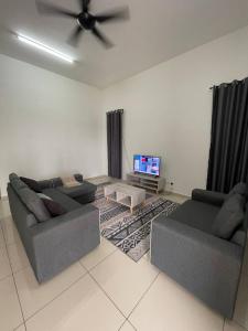 a living room with two couches and a flat screen tv at BUNGALOW homestay JASIN PERDANA in Jasin