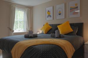 um quarto com uma cama grande e almofadas amarelas em Luxury 2-bedroom 2-bathroom city centre apartment em Lichfield