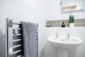 een badkamer met een wastafel en een handdoek op een koelkast bij Luxury 2-bedroom 2-bathroom city centre apartment in Lichfield