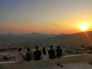 Un gruppo di persone sedute su un cornicione a guardare il tramonto di Cozy House a Wadi Musa