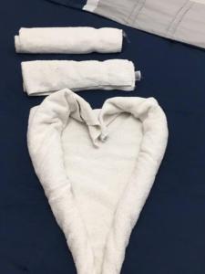 a white towel in the shape of a heart next to towels at Cozy House in Wadi Musa