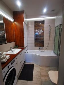 ein Badezimmer mit einer Badewanne, einem Waschbecken und einer Waschmaschine in der Unterkunft K&Scielna4013 in Świdnica
