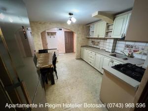 une cuisine avec des placards blancs et une table. dans l'établissement Apartament Ultra Modern 2 camere mari +1 camera mai mica, à Botoşani
