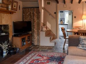 a living room with a television and a staircase at Cosy Cottage in Bourton on the Hill