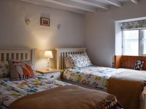 a bedroom with two beds and a window at Cosy Cottage in Bourton on the Hill