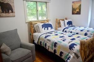 a bedroom with two beds and a chair and a window at Escape to a 3-Bedroom Cabin in Lower Catskills in Woodridge