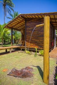 ein Holzgebäude mit einem Brunnen in einem Park in der Unterkunft Cabana Fluir - Taipu de Fora - Península de Maraú in Barra Grande