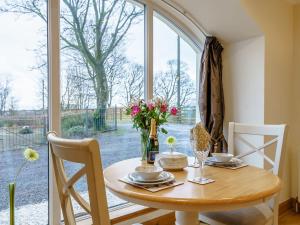 a dining room table with flowers and a large window at Little Arches - S4665 in Lochwinnoch