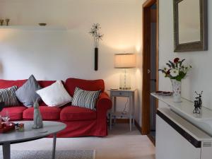 a living room with a red couch and a table at Tree Tops in Crieff