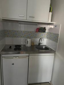 Elle comprend une petite cuisine avec des placards blancs et un évier. dans l'établissement Cosy appartement with free parking a Paris, à Villejuif