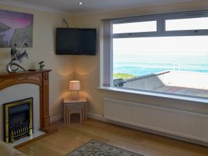 a living room with a fireplace and a large window at Dolphin View - Uk30689 in Portknockie