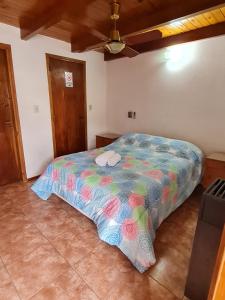 - une chambre avec un lit et une couette colorée dans l'établissement Giovanni Luigi, à Villa General Belgrano