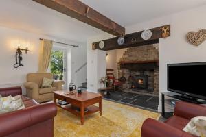 a living room with a couch and a fireplace at Stable Cottage - QC1789 in Llandyssiliogogo