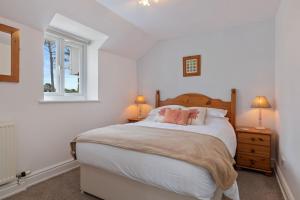 a bedroom with a bed with two lamps and a window at Stable Cottage - QC1789 in Llandyssiliogogo