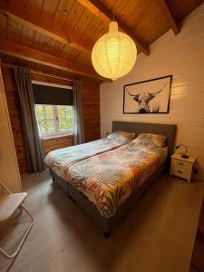 a bedroom with a bed and a chandelier at Veluwse Bungalow in Ermelo