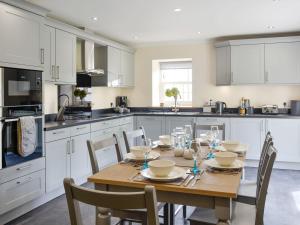 a white kitchen with a wooden table and chairs at The Stables - Uk11108 in Montrose