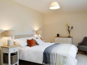 um quarto com uma grande cama branca e uma cadeira em The Stables - Uk11108 em Montrose