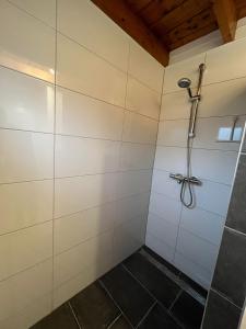 een douche in een badkamer met witte tegels bij Veluwse Bungalow in Ermelo