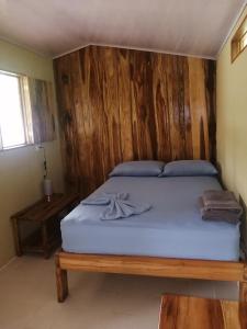 ein Schlafzimmer mit einem Bett mit einer Holzwand in der Unterkunft El Gecko Hotel & Tours in Paquera